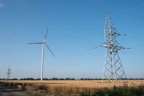 風車はエネルギーを生み出す 風力タービンは 自然エネルギーで発電した再生可能エネルギーとクリーンエネルギーで送電線をサポートしています — ストック写真