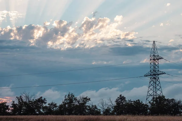 Power transmission lines transfer clean energy. Power substation delivers renewable energy from windmill to farmlands against blue sky with clouds