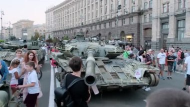 KYIV, UKRAINE - 24 Ağustos 2022: Meraklı insanlar Kyiv 'in merkezinde duran imha edilmiş Rus tankını inceliyorlar. Çocuklar ve yetişkinler askeri sergiye yavaş çekimde bakarlar.