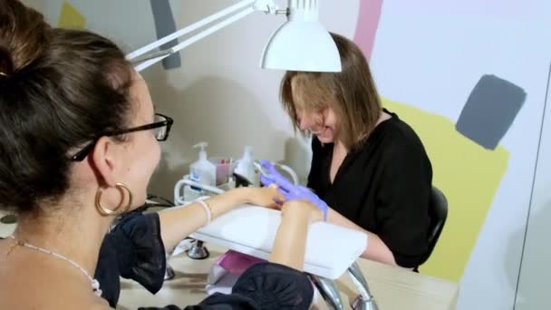 Jonge Vrouw Met Bril Ondergaat Manicure Zittend Een Moderne Schoonheidssalon — Stockvideo