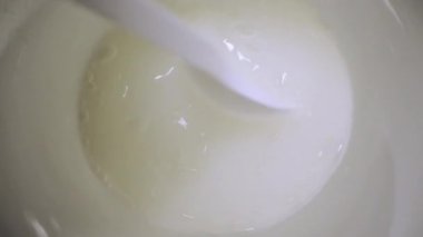 Person mixes powder with water in bowl to prepare remedy to handle flue. Preparation of anti-inflammatory solution with spoon extreme closeup
