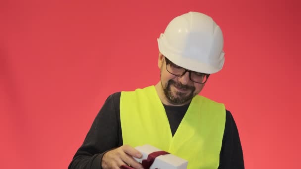 眼鏡の正の労働者は 現在のボックスを保持手を伸ばし 赤の背景のクローズアップでプロの制服のひげそりの専門家 — ストック動画