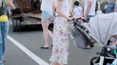 KYIV, UKRAINE - 24 AĞUSTOS 2022: Yetişkinler ve çocuklar Kyiv 'in merkezinde imha edilmiş Rus askeri teçhizatının yakınında yürüyorlar. İnsanlar Khreshchatyk Caddesi 'ndeki sergiyi ziyaret ediyor.
