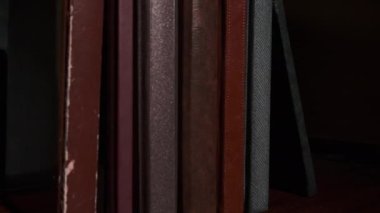 Siyahi arka planda renkli pejmürde kapaklı eğitici kitaplar. Popüler edebiyat, halk kütüphanesine yakın bir görünümde rafta duruyor