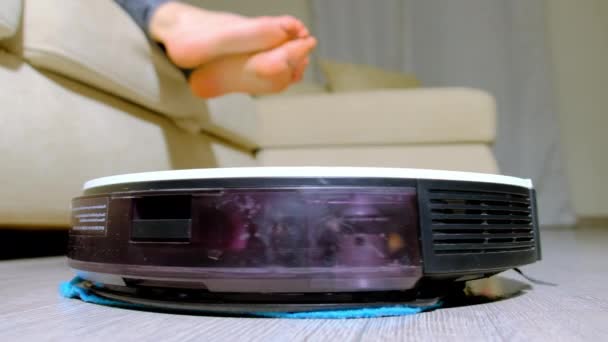 Ρομπότ Κενό Καθαρίζει Laminate Πάτωμα Στο Σαλόνι Κατά Ξυπόλυτη Γυναίκα — Αρχείο Βίντεο