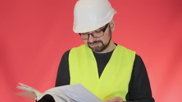 身穿白色硬礼帽的工程师满意地展示了阅读项目文件的姿态 留胡子的工人靠着红墙的特写翻页 — 图库视频影像