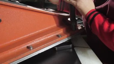 Bayan terzi, büyük siyah deri kumaştan kredi kartı kılıfını kesiyor ve yakın plan çekime basıyor. Tasarım sanatını kavra