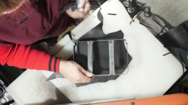 Yaşlı kadın, küçük siyah deri kumaş parçasında metal cüzdan kalıbı ölçüyor ve üst görüşü kesmek için basını hareket ettiriyor. Kavram sanatı