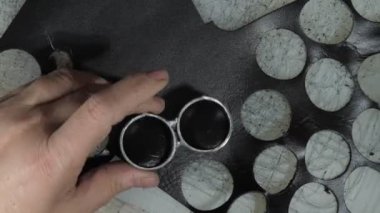 Terzi, metal bıçaklı küçük deri kredi kartı elementlerini kesiyor ve ayrıntıları büyük yığına koyuyor.