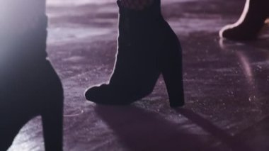 Siyah topuklu ayakkabılarla erotik performans ve ışıklı gece kulübü sahnesinde file çoraplar. Bir grup dansçı yakın çekim çalışması yapıyor.