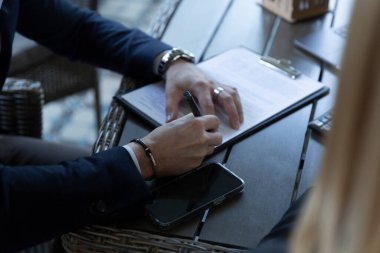 Muhtemel müşteri satış anlaşmasını ahşap masa kapanışında imzalıyor. İş adamı profesyonel emlak acentasıyla anlaşmaya hazır.