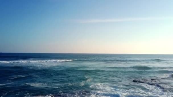 无边深蓝色海水的全景 无边无际的大海 平静的小海浪冲击着清澈天空下的岩石海滩 — 图库视频影像
