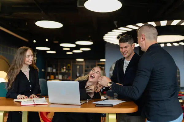 Business colleagues discussing office work in modern company. Office workers laughing during small talk between paperwork
