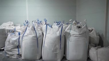 Boş depoda mikro plastik granüllerin depolandığı büyük çantalar. Fabrika zemininde büyük çuvallarda geri dönüşümlü polyester malzemeler üretiliyor.