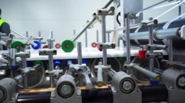 Otomatik üretim hattı fabrika atölyesinde plastik pencere pervazını polimer folyoyla kaplıyor. Endüstriyel tesislerdeki makinelerle modern silindir üretimi