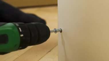 İşçi, odasının yanındaki çekmeceye vida sıkıştırmak için elektrikli tornavida kullanıyor. Yüzeyle hasarsız başa çıkmak için özel bir aygıt