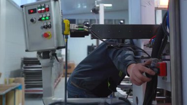 İşçi fabrika kapandığında otomatik üretim hattındaki durdurma düğmesine basıyor. Çalışanların kontrolleri atölyedeki panel ile çalışma ayarlama makinesi