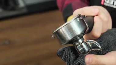 Deneyimli barista iskele filtresini silmek için bez kullanıyor. Ağır çekimde temizlik gerektiren belirli bir alanı temizleyen adam.