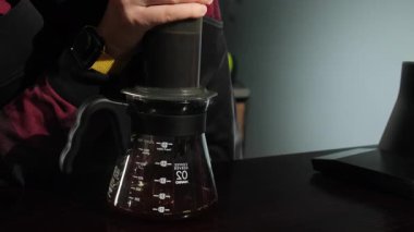 Barista şeffaf sürahiye damlatılmış kahve damlatıyor ve cam pourover tutuyor. Modern kahve makineleriyle kahve hazırlama.