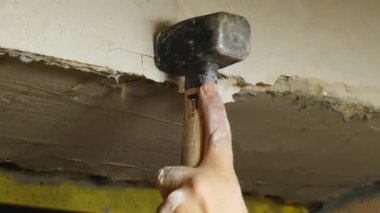 Erkek işçi duvardaki eski alçı tabakasını sökmek için çekiç kullanır. Zanaatkar yeni inşaat işleri için yüzey temizleme alanını dikkatlice yıktı