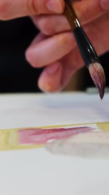 Sanatçı, manken şekillendirme figürünü resmetmeyi öğreniyor. Uzman, detaylar üzerinde çalışan araçla suluboya fırça kullanır ve çarşaf yüzeyine dokunur