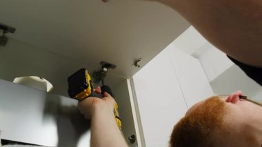 Mobilya montajcısı menteşeyi tornavida kullanarak kurar. Sakallı profesyonel çalışmalar küçük elementlerin düzeltilmesi ve dikkatle izleme mekanizmasının izlenmesi üzerine