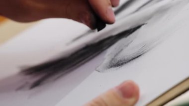 İnsanoğlu aktif olarak siyah lekeyi beyaz kağıda çizer ve harmanlayarak manken yaratır. Kömür içeren sanatsal sürecin dokunsal doğası