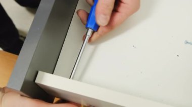 Profesyonel kurucular çekmeceye vida takar ve kontrol eder. Mobilya montaj uzmanı, tornavida kullanılarak mekanizmanın pürüzsüzlüğünü ve güvenilirliğini analiz eder