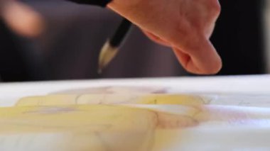 Yaratıcı, manken resmi yapmak için fırça darbeleri uyguluyor. Sanatçı, figürün ifade gücünü ve benzersizliğini vurgulayan unsurlar yaratmak için fırça kullanır