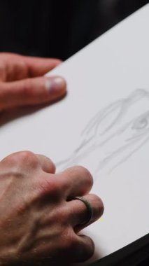 Adam çizim tekniği kullanıyor. Kağıda manken çiziyor. Adam siluet yaratmaya çalışıyor ve yaratıcı kulüpte özel araç harcaması yapıyor.