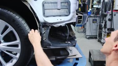 Teknisyen aracın vücut yüzeyinin durumunu belirlemek için araç kullanıyor. Adam, otomobil taşıma aracının sabitleme kısmında çalışıyor.