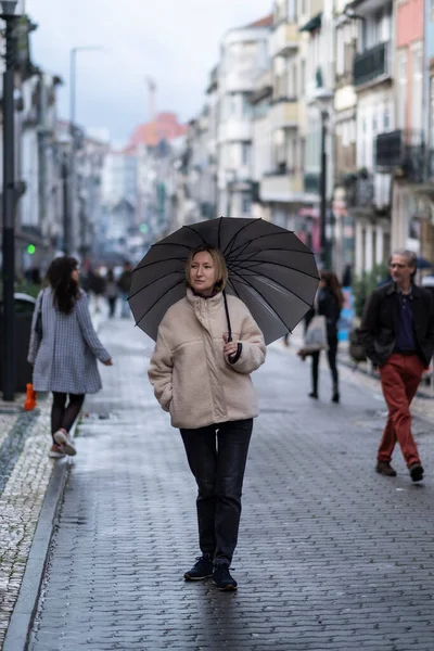 ポルトガルのポルトのダウンタウンにあるサンタカタリーナ通りに傘を持っている女性 — ストック写真