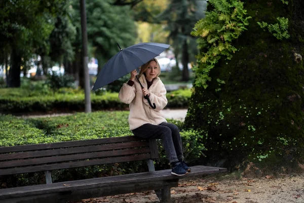 Uma Mulher Com Guarda Chuva Senta Banco Parque — Fotografia de Stock