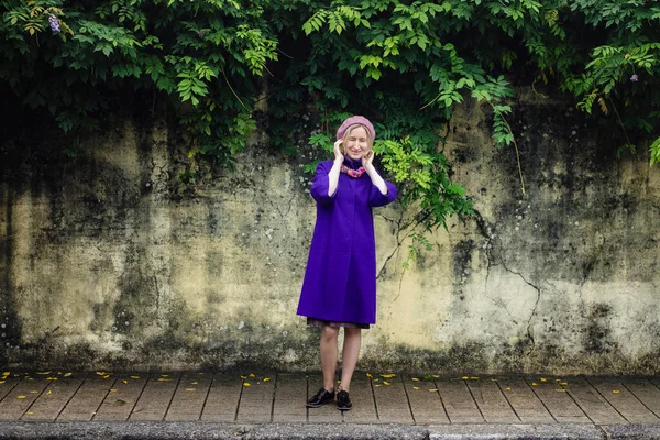 一个身穿外套 头戴贝雷帽的女人站在墙边的人行道上 — 图库照片