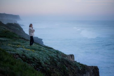 Bir kadın sabahın erken saatlerinde Atlantik kıyısında duruyor..