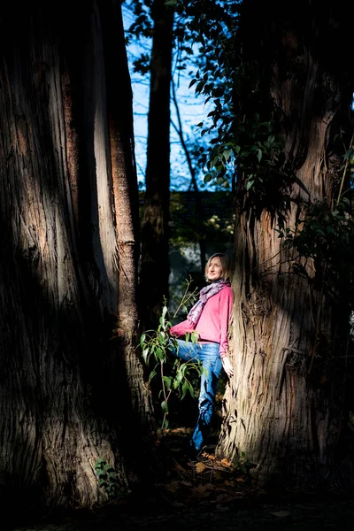 Žena Stojí Mezi Dvěma Stoletými Stromy Parku — Stock fotografie