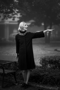 Sokakta duran tanıdıklarına el sallayan bir kadın. Siyah beyaz fotoğraf.