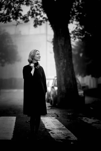 一个女人站在秋天花园附近的人行道上 黑白照片 — 图库照片
