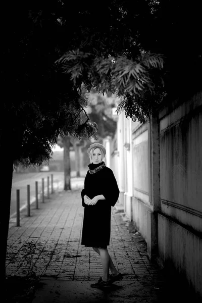 在城市的人行道上站着一个穿着秋衣和贝雷帽的时髦女人 黑白照片 — 图库照片