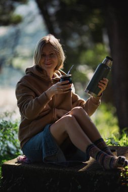 Parkta elinde Mate Cup ve termosla bir kadın..