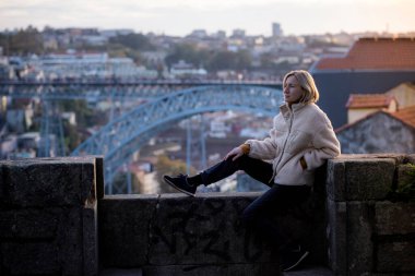 Portekiz, Porto 'nun merkezindeki taş duvarda bir kadın oturuyor..