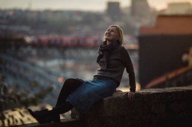 Portekiz, Porto 'da antik bir taş duvarda bir kadın oturuyor..