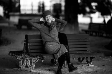 Portrait of a woman resting on a park bench. Black and white photograph.
