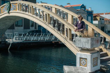 A woman stands near the bridge on Ria de Aveiro canals. Portugal.