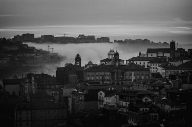 Alacakaranlıktaki eski şehir merkezinin sisli manzarası, Porto, Portekiz. Siyah beyaz fotoğraf.