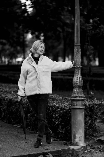 一个拿着雨伞在公园里散步的女人 黑白照片 — 图库照片