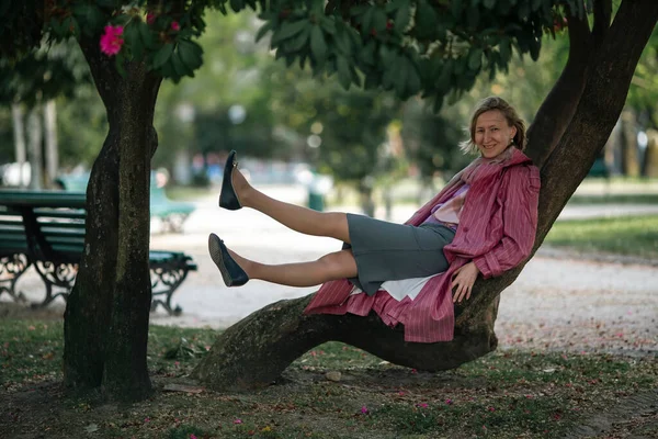 一位穿着80年代风格的粉色雨衣的女士在公园里摆姿势 — 图库照片