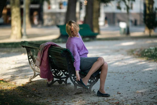 Una Donna Seduta Una Panchina Scuote Ciottolo Dalla Scarpa — Foto Stock