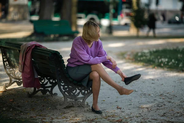 Una Donna Siede Una Panchina Del Parco Toglie Scarpe — Foto Stock
