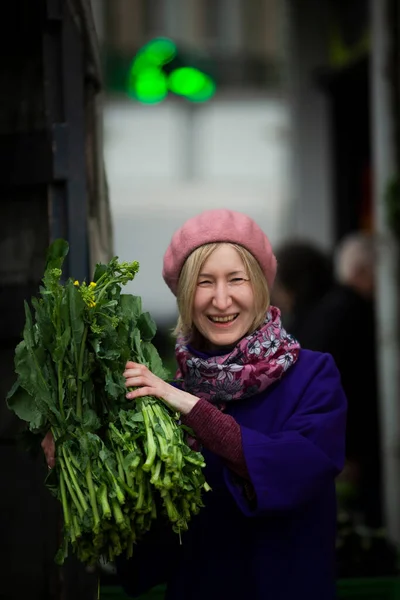 街上商店里一个笑容满面 快乐的女人购买并展示美味的绿色 — 图库照片